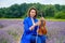 Full body adult woman violinist playing violin and sitting on lavender field