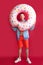 Full body cheerful tourist man holds inflatable ring look camera isolated on red background.