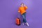 Full body length cadre of satisfied business model traveling around world with orange new valise isolated on purple