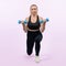 Full body length shot active and sporty senior woman lifting dumbbell. Clout