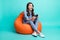 Full body photo of amazed charming young woman amazed game sit chair isolated on teal color background