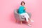 Full body photo of attractive young woman armchair hold device look empty space wear trendy blue clothes isolated on