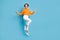Full body photo of attractive young woman jumping graceful dance have fun wear trendy orange garment isolated on blue