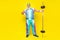 Full body photo of cheerful aged person put hand waist hold barbell isolated on yellow color background