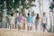 Full body photo of company peaceful friendly people hold arms walk sand beach outdoors