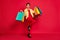 Full body photo of cool lucky charming woman hold hands purchases bags smile win isolated on red color background