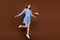 Full body photo of funky brunette lady jump with flowers wear blue dress isolated on brown background