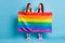 Full body photo of funny tricky lesbians couple visit foreign parade support same sex marriages hold gay rainbow flag