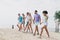 Full body photo of six peaceful positive people hold arms walking sand beach weekend outdoors