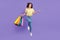 Full body photo of unsure young brunette lady jump do shopping wear yellow top jeans sneakers isolated on violet color