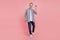 Full body photo of young handsome guy go walk step happy positive smile waving hello isolated over pink background