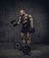 Full body portrait of bodybuilder with dumbbells in a studio.