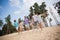 Full body portrait of group funky excited buddies hold arms running sand beach enjoy journey forest outside