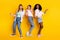 Full body portrait of three carefree charming girls have fun weekend partying isolated on yellow color background