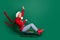 Full body profile photo of excited santa young lady ride on sled wear sweater jeans boots isolated on green background