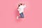 Full body profile photo of young lady jump wear hoodie jeans sneakers isolated on pink background