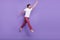 Full body profile portrait of carefree barefoot guy raise fist look interested empty space isolated on violet color