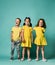 Full body shot of three children in bright clothes, two girls and one boy. Triplets, brother and sisters.