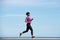 Full body side fit young african woman running outdoors against blue sky