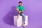 Full body size photo of young cheerful guy sitting platform good mood waiting changing room isolated on violet color