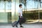 Full body smiling handsome man walking outside with suitcase