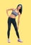 Full body of young happy smiling blue haired slim woman doing fitness stretching exercise. Yellow background