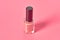 Full bottle of luxury nail polish on pink background