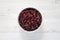 Full bowl of dry organic cranberries over white wooden surface, top view. Overhead, from above, flat lay. Close-up