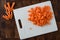 Full and chopped baby carrots on a white cutting board on wood butcher block