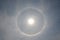 Full circle rainbow around Sun at noon, rays catch the thin vapour formed of ice crystals