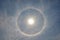 Full circle rainbow around Sun at noon, rays catch the thin vapour formed of ice crystals