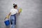 Full disinfection. Back view of housewife or maid woman uniform and yellow rubber gloves holding bucket with different