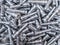 Full frame background of pile of shiny long steel parts, clean steel rods after fine cnc turning - laying chaotically