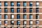 Full frame of brick facade of residential building with array of rectangular windows