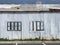 full frame close up of a shabby old dilapidated corrugated iron building with with closed painted over patched windows repaired