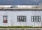 full frame close up of a shabby old dilapidated corrugated iron building with with closed painted over patched windows repaired