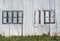 full frame close up of a shabby old dilapidated corrugated iron building with with closed painted over patched windows and white