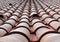 Full frame diminishing perspective view of an old roof with curved clay red tiles in lines with ventilation slots