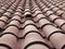 Full frame diminishing perspective view of an old roof with curved clay red tiles in lines with ventilation slots