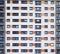 a full frame image of windows in a large high rise apartment building with repeating rows of windows with white walls with orange