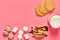 Full glass of fresh milk, yogurt or kefir near thin waffles, chocolate candies, marshmallow on pink background. Space for text