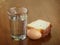 A full glass of water, egg and two slices of bread on an scratched wooden table