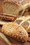 Full grain bread roll on wooden table with ear of rye