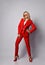 Full growth portrait of young sensual blonde woman in elegant deep red official suit, sunglasses and shoes