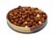 Full hazelnuts in a brown wooden bowl  on white background, selective focus