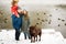 Full height family portrait with one kid and dog in winter casual outfit posing outdoors near river with duck birds