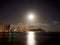 Full Large Moon hangs over Diamond Head Crater, Waikiki hotels, and Marina at Night