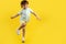Full lengh photo of funny kid listening music in headphone and dance over yellow background.