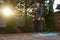 Full length active man, sportsman yogi standing barefoot on a blue fitness mat while practicing yoga outdoors at sunset