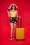Full length of attractive young female in traveller casual with the travel bag, holding passport on hand isolated on red